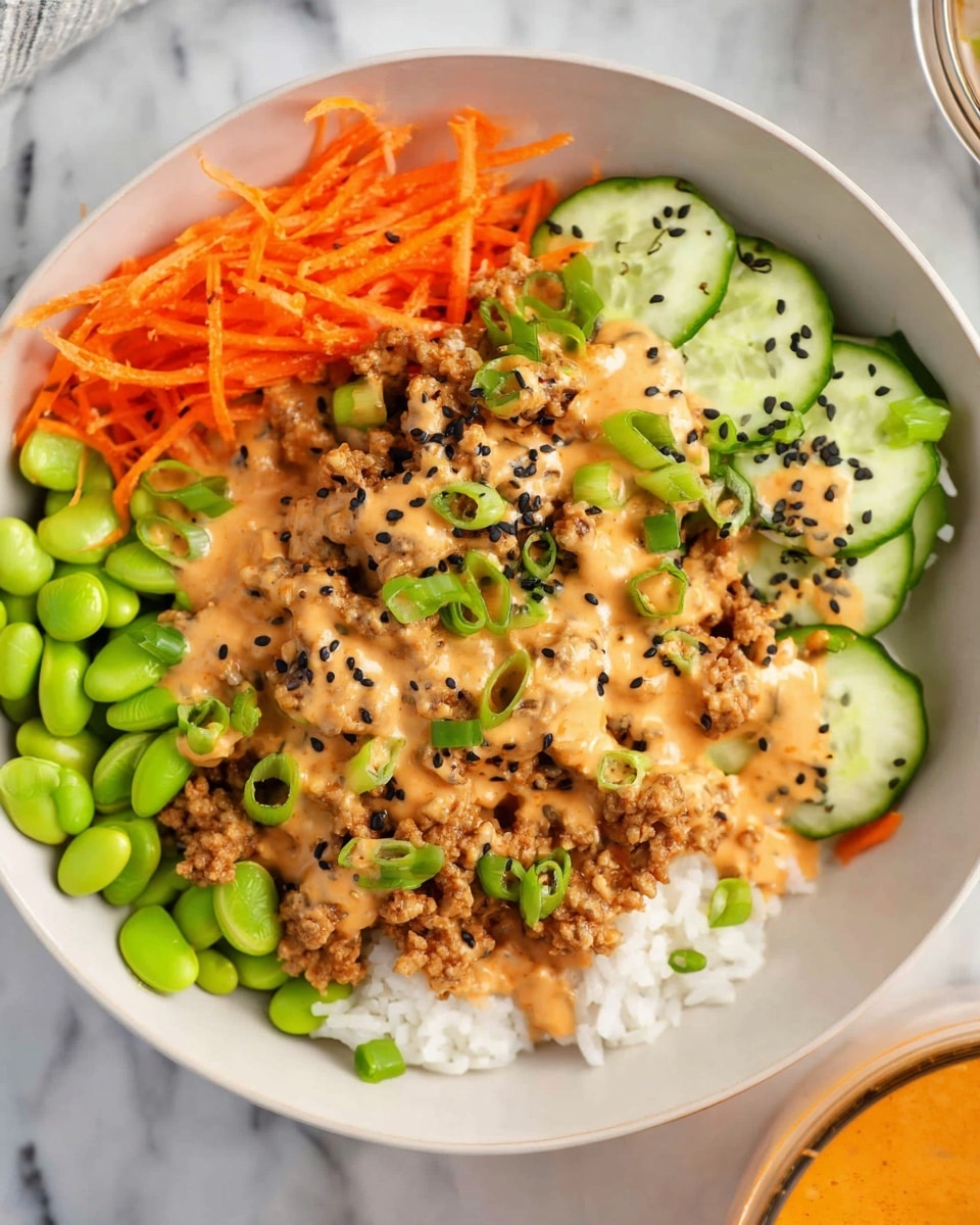 A white bowl holds a layered dish starting with a base of white rice at the bottom left, topped with bright green edamame beans scattered on the rice. Next to the rice and edamame is a portion of cooked ground meat covered with a creamy orange sauce, sprinkled with black sesame seeds and green chopped scallions. On the top right side of the bowl, there are thin slices of fresh cucumber with black sesame seeds, and on the far left, shredded orange carrots add a bright color contrast. The bowl rests on a white marbled surface, and part of a glass container filled with the same orange sauce is visible at the bottom right corner. photo taken with an iphone --ar 4:5 --v 7