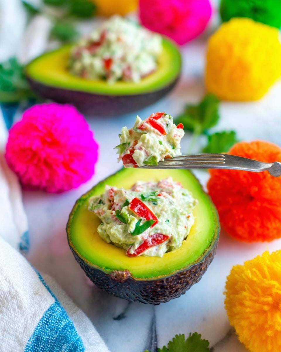 The image shows a three-layered dish placed on a white marbled surface. The bottom layer has chunky bright green avocado pieces with a soft texture. The middle layer is creamy and white, appearing like shredded chicken mixed with some herbs. The top layer is a mixture of finely chopped bright red tomatoes and small white onion pieces, glistening with freshness. A black fork is pushed into the top layer, adding a sense of action. Behind the dish, a halved avocado and a lime wedge are visible, both resting on the white marbled surface. Photo taken with an iphone --ar 4:5 --v 7