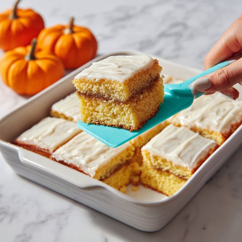 The image shows a two-layer square piece of yellow cake with an orange filling between the layers. The top layer is covered with a thin white icing that looks slightly shiny and cracked. The cake piece is placed on a white plate with a subtle pattern, sitting on a white marbled surface. A fork with a dark red handle is on the plate, holding a small piece of cake. In the background, there is a glass of milk and another piece of cake, slightly out of focus. The lighting highlights the moist texture of the cake and the shiny icing. photo taken with an iphone --ar 4:5 --v 7