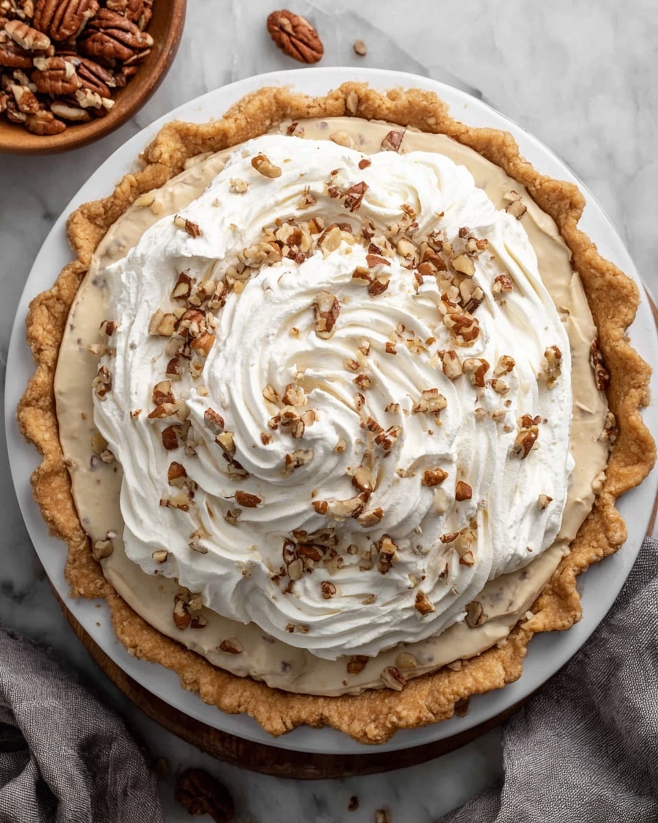 A slice of pie being lifted from a white pie dish on a white marbled surface. The pie has three layers: a golden, flaky crust at the bottom; a thick, creamy beige filling in the middle that looks smooth and soft; and a generous layer of fluffy white whipped cream on top, sprinkled with chopped pecans. The pie slice is held by a wooden-handled pie server, with some of the filling and cream clearly visible on the cut edges. The background is warm and blurred, making the pie the main focus. Photo taken with an iphone --ar 4:5 --v 7