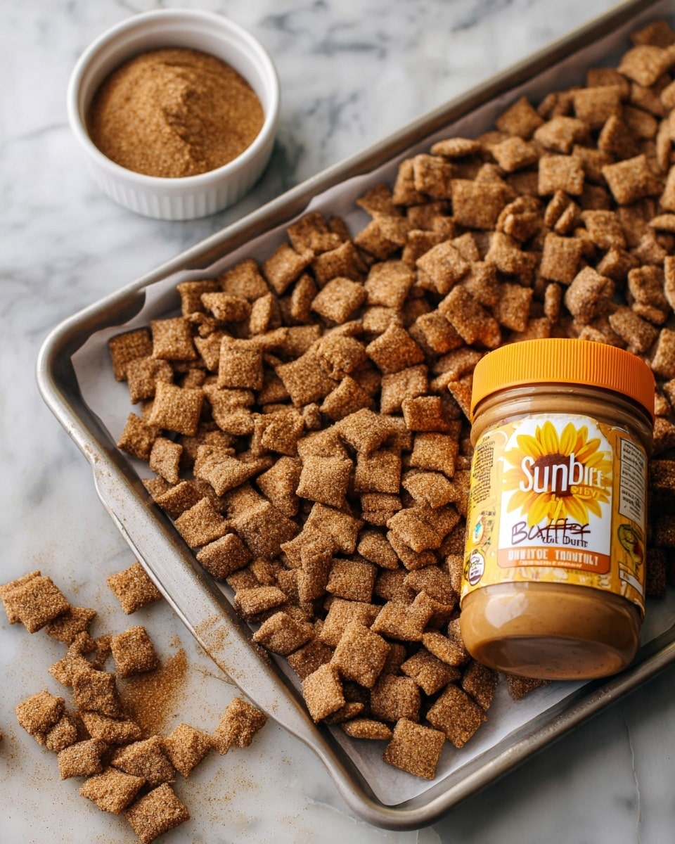 The image shows a close-up view of small, square-shaped snack pieces that are coated with a fine layer of seasoning. Each piece is light brown with visible specks of darker seasoning, giving them a rough and textured look. The squares are piled together, with some pieces overlapping each other. The background is blurred, highlighting the texture and color of the snack in the foreground. The overall color is a warm brown with a grainy surface, showing the seasoning's powder clearly. Photo taken with an iphone --ar 4:5 --v 7