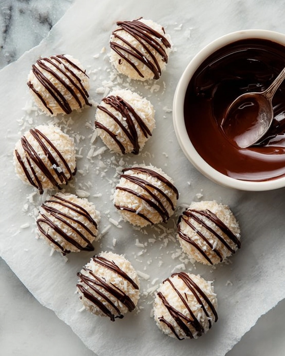 The image shows several round coconut-covered balls with a smooth, brown chocolate filling visible in one ball that is cut open in front. Each ball is covered in white shredded coconut flakes, giving a rough texture on the outside and is drizzled with shiny dark brown chocolate lines on top. The cut ball reveals the creamy chocolate layer inside, with some melted chocolate oozing out onto a dark wooden board below. The balls are arranged closely together on the board with a white marbled background visible around the edges. photo taken with an iphone --ar 4:5 --v 7