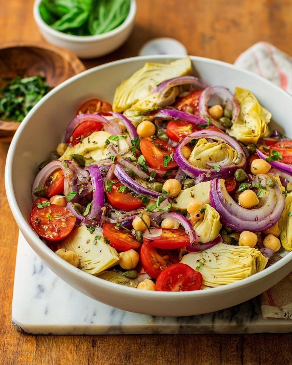 A white bowl filled with a fresh salad sits on a white marbled surface, surrounded by an orange cloth and small bowls of chopped green herbs and fresh basil leaves. The salad contains several layers including light green artichoke hearts cut into quarters, bright red halved cherry tomatoes, thinly sliced purple-red onion rings, pale yellow chickpeas scattered throughout, and small green chopped herbs sprinkled on top. A silver spoon rests inside the bowl, slightly buried in the salad. The salad's colors and textures create a vibrant, fresh look. photo taken with an iphone --ar 4:5 --v 7