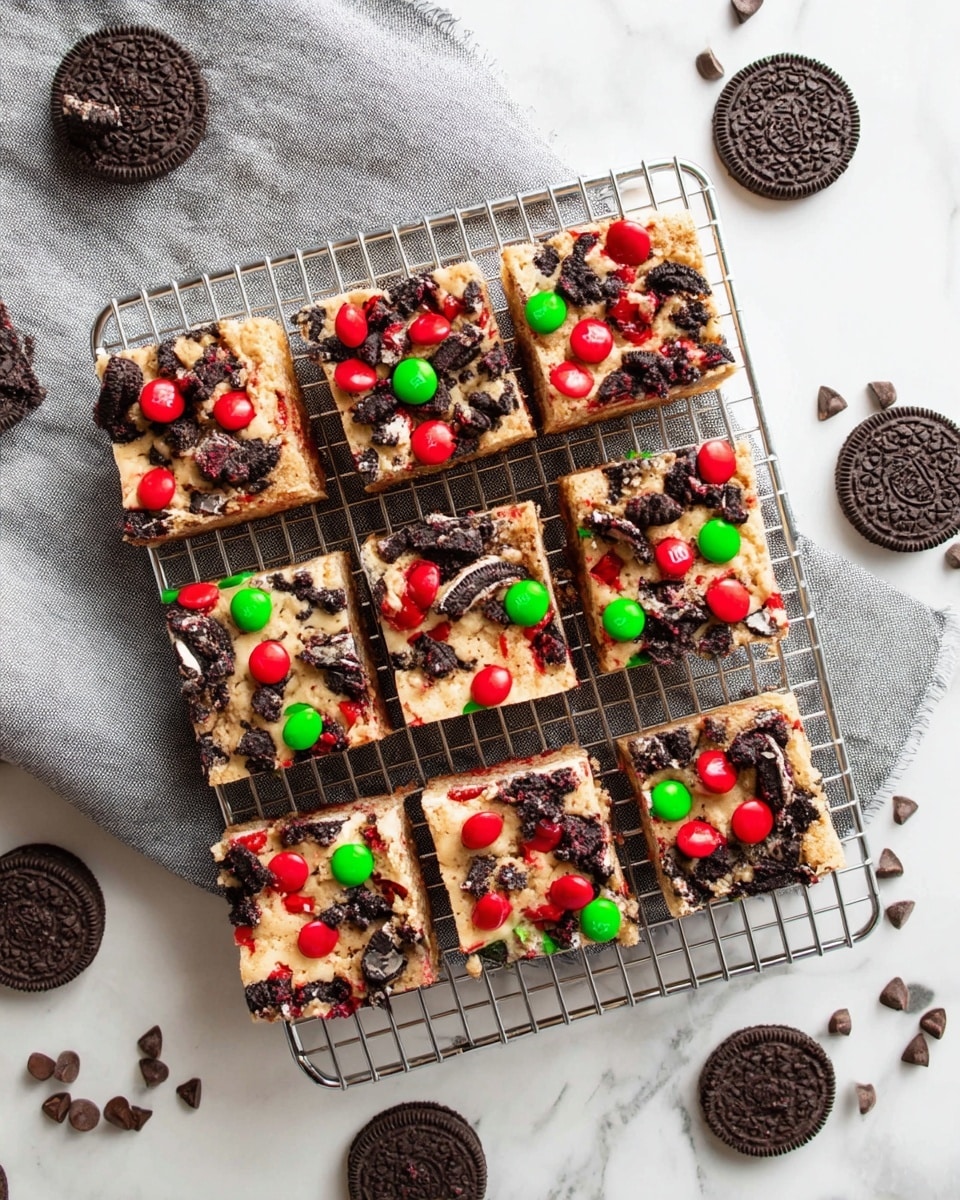 The image shows close-up pieces of a thick, square dessert bar on a white marbled surface, each piece having a rough, textured top layer filled with colorful candy pieces and cookie chunks. The top layer is light golden brown with visible green and red candy-coated chocolates, dark chocolate chips scattered throughout, and broken black cookie pieces with cream filling. The base layer looks dense and fudgy, dark brown with melted chocolate patches visible inside. Some pieces have slightly cracked edges revealing the gooey, chocolate-filled center. Photo taken with an iphone --ar 4:5 --v 7