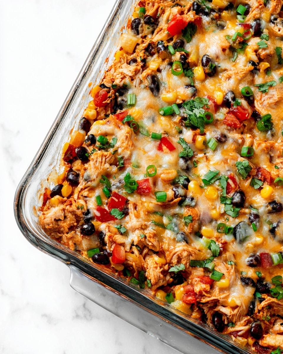 The image shows a close-up of a baked dish in a clear glass rectangular pan filled with a mix of shredded chicken, black beans, corn kernels, and red bell peppers. The dish is topped with melted cheese that lightly browns in places, mixed evenly with chopped green onions and fresh cilantro, giving a pop of green color. All ingredients are mixed together creating a colorful, textured surface with small visible layers of melted cheese and vegetables. The background is a white marbled texture. photo taken with an iphone --ar 4:5 --v 7