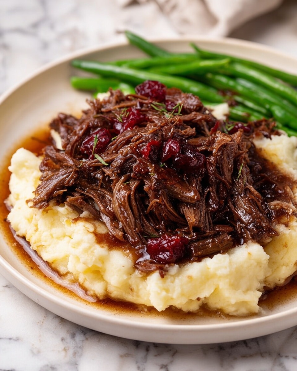 A close-up view of tender, shredded meat with a rich, dark brown color, held by wooden tongs lifting some strands above a pile of the same meat in a white bowl. The meat strands appear juicy and glossy with a slightly sticky texture, showing a mix of deep reddish and brown hues, with visible small pieces of onions or spices tangled in the fibers. The background and surface around the bowl show a soft focus, highlighting the meat’s moist and succulent detail. Photo taken with an iphone --ar 4:5 --v 7