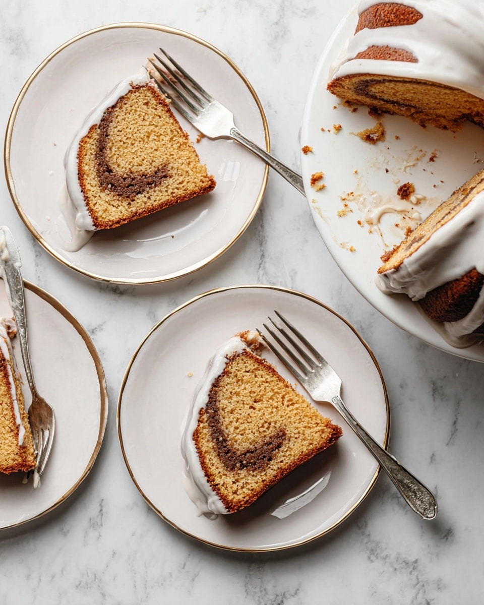 A thick slice of bundt cake rests on a white plate with a thin silver rim, showing two layers: a golden brown outer layer and a darker brown swirl running horizontally inside. A thick white glaze drips down from the cake onto the plate, adding a shiny texture to the bottom layer. Behind the slice, the rest of the bundt cake sits on a white marble cake stand with a light wood base, also covered with white glaze that drips down its sides in uneven streams. The scene is set on a white marbled surface with a stack of white plates in the background, and a silver fork lies beside the slice. Photo taken with an iphone --ar 4:5 --v 7